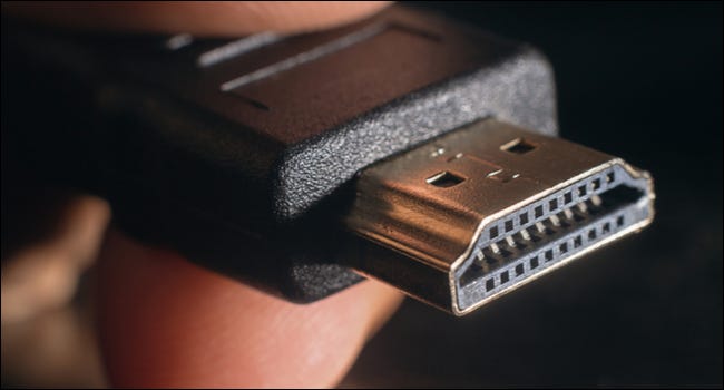 人的手指之间的 HDMI 连接器的特写。